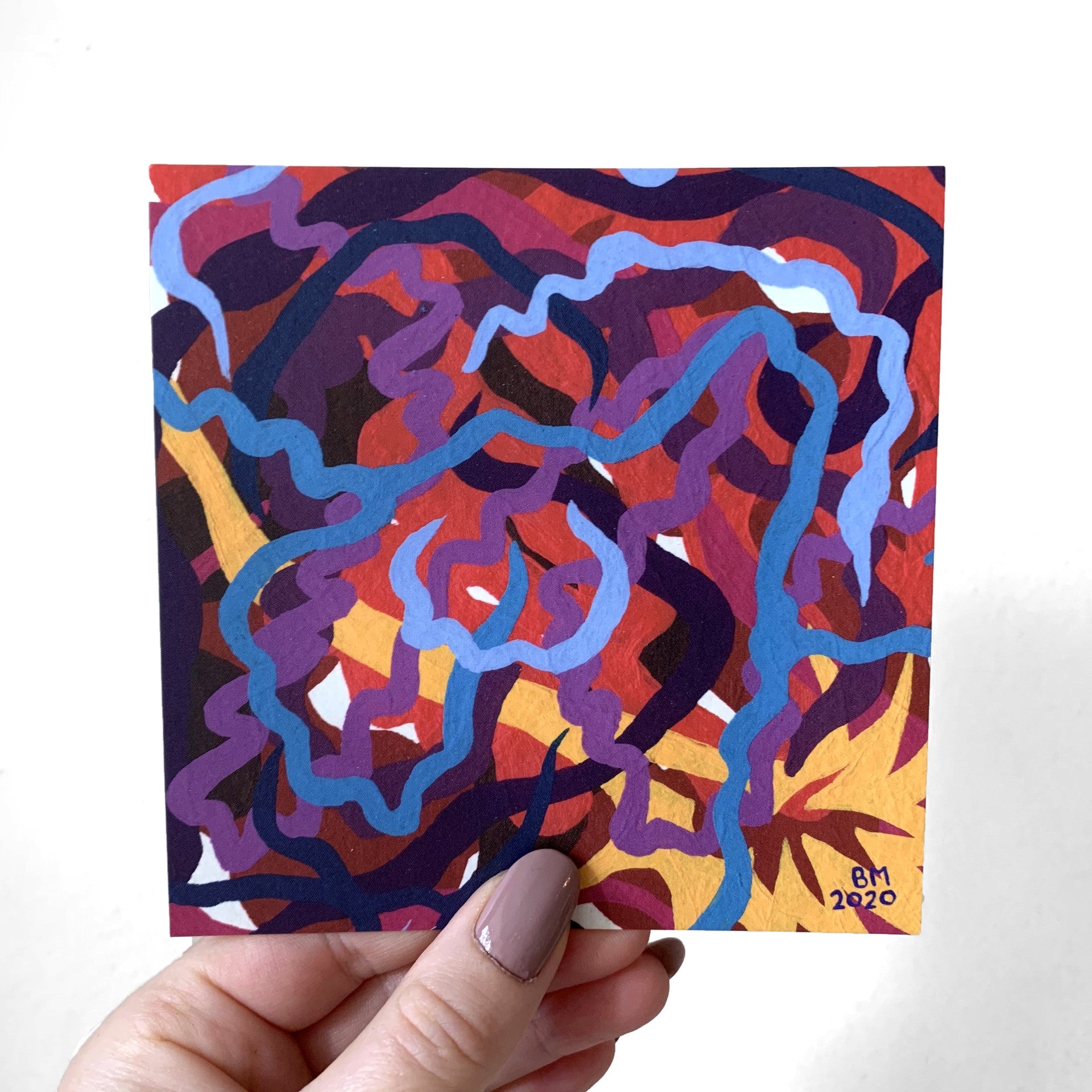 A hand holding a square print against a white background. The print consists of swirling abstract shapes in shades of purple, red and blue with a yellow line cutting amongst these shapes. The initials BM and the year 2020 are written in the bottom right corner.  